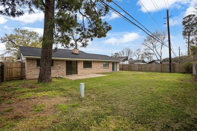 back of property with brick siding, a lawn, a patio, and a fenced backyard