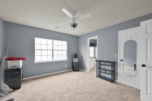 misc room with a textured ceiling, light colored carpet, and ceiling fan