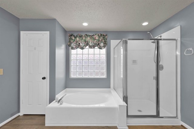 bathroom with independent shower and bath, a textured ceiling, and wood-type flooring