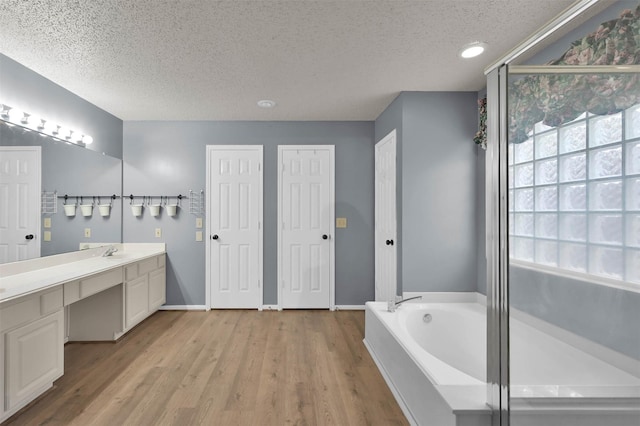 bathroom featuring vanity, a tub, hardwood / wood-style floors, and a textured ceiling