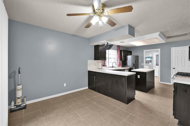 kitchen with a textured ceiling, stainless steel refrigerator with ice dispenser, sink, kitchen peninsula, and ceiling fan