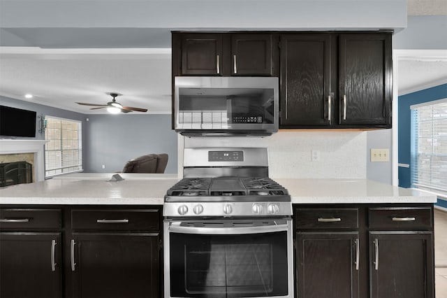 kitchen with ceiling fan, dark brown cabinetry, stainless steel appliances, and tasteful backsplash