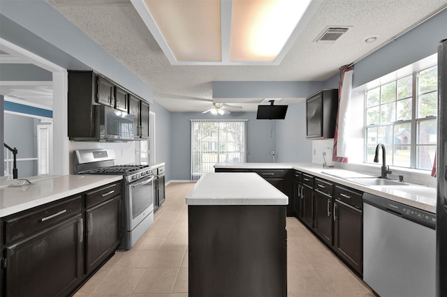 kitchen with ceiling fan, sink, kitchen peninsula, stainless steel appliances, and light tile patterned flooring