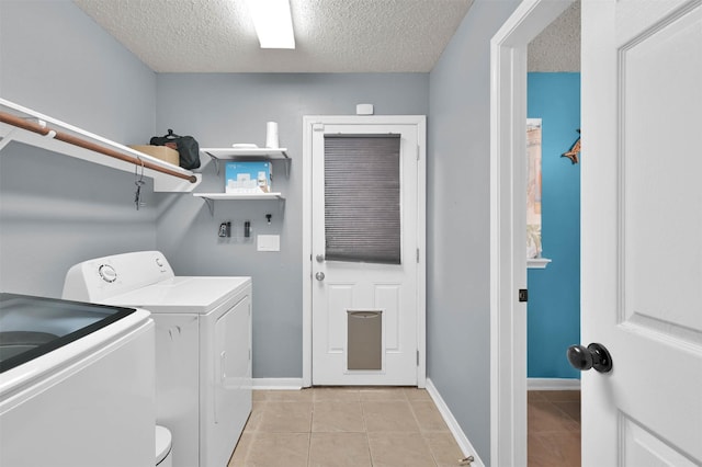 washroom with light tile patterned floors, a textured ceiling, and washer and clothes dryer