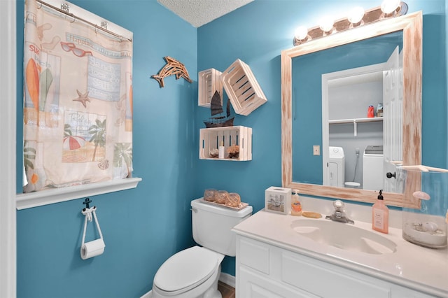 bathroom with a textured ceiling, washer and clothes dryer, vanity, and toilet