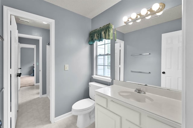 bathroom with vanity, toilet, and a textured ceiling