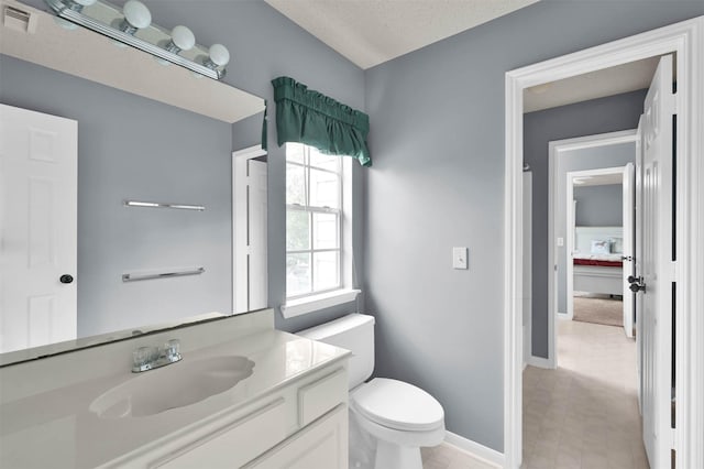 bathroom with toilet, a textured ceiling, and vanity