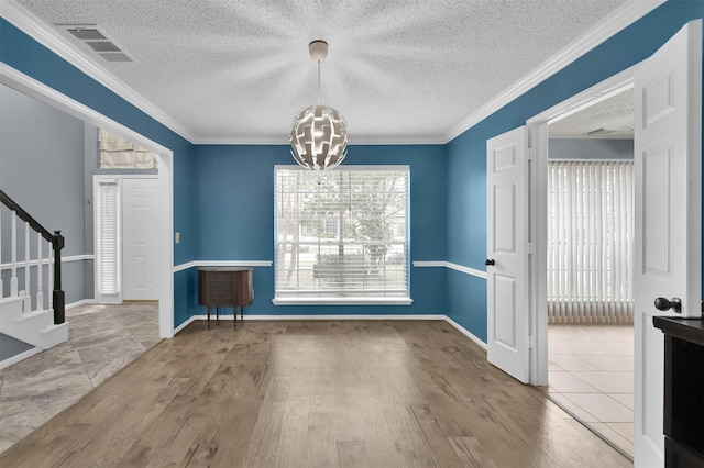 unfurnished dining area with a chandelier, crown molding, a textured ceiling, and tile patterned flooring