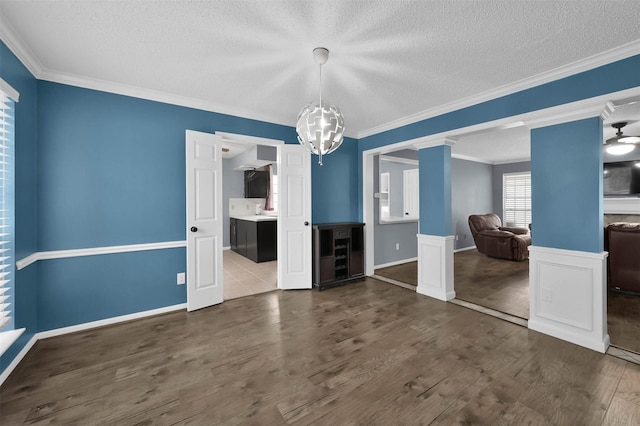 unfurnished dining area featuring decorative columns, hardwood / wood-style flooring, a chandelier, and ornamental molding