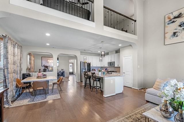 kitchen with pendant lighting, appliances with stainless steel finishes, white cabinets, a kitchen island, and a breakfast bar area