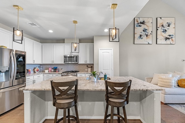 kitchen with white cabinetry, appliances with stainless steel finishes, and an island with sink