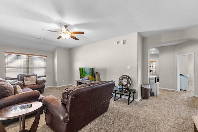 living room with light carpet, a textured ceiling, and ceiling fan