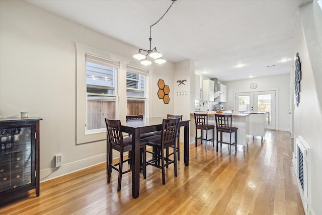 dining room featuring wine cooler, french doors, and light wood-type flooring