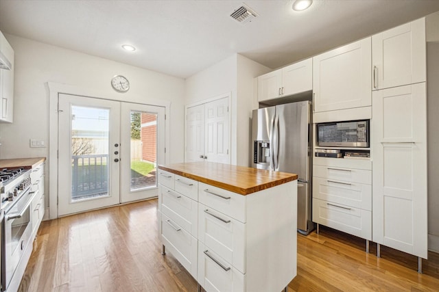 kitchen with white cabinetry, appliances with stainless steel finishes, light hardwood / wood-style floors, and butcher block countertops