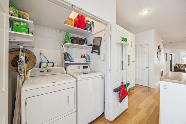 laundry area with washer and clothes dryer and light wood-type flooring