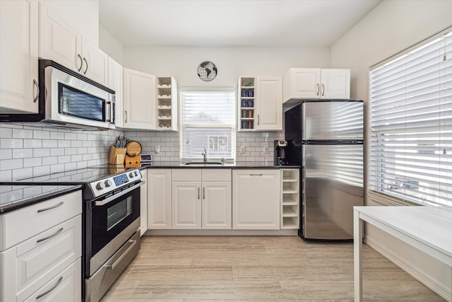 kitchen with white cabinetry, stainless steel appliances, sink, and tasteful backsplash