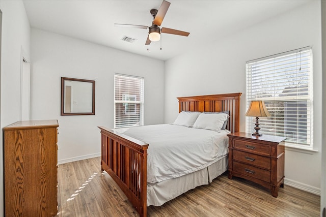 bedroom with multiple windows, ceiling fan, and light hardwood / wood-style floors