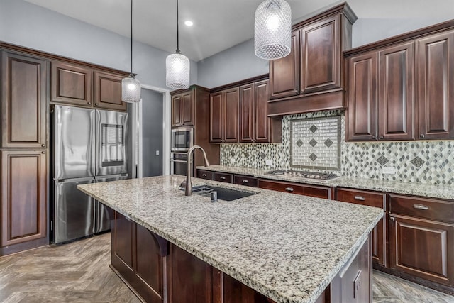 kitchen with hanging light fixtures, sink, stainless steel appliances, a center island with sink, and dark brown cabinetry