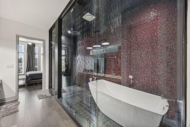 bathroom with hardwood / wood-style flooring, a towering ceiling, and shower with separate bathtub