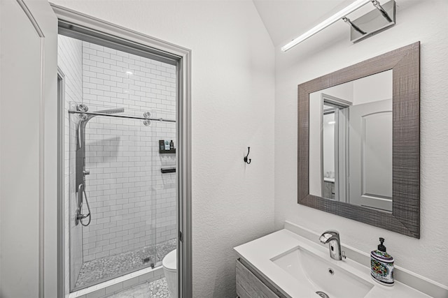 bathroom with a tile shower, toilet, lofted ceiling, and vanity