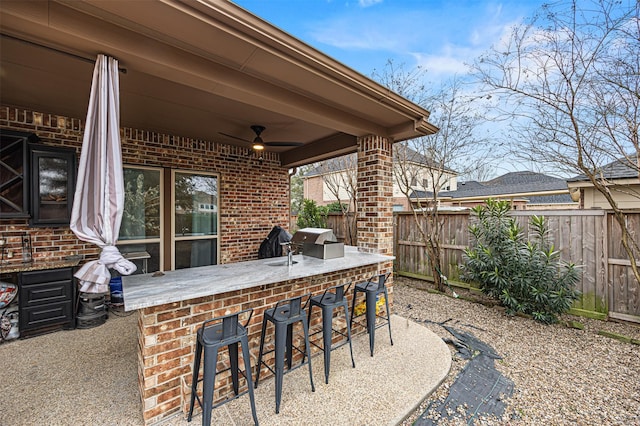 view of patio / terrace with ceiling fan, a bar, and a grill