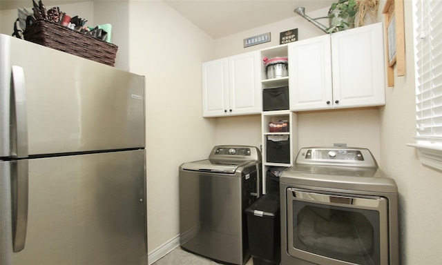 clothes washing area featuring washing machine and clothes dryer and cabinets