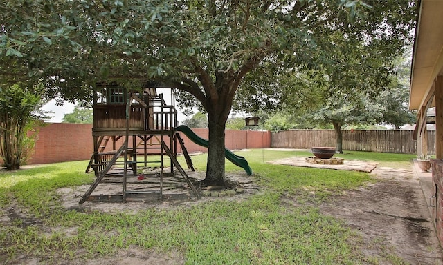 view of jungle gym featuring a patio area, a yard, and a fire pit