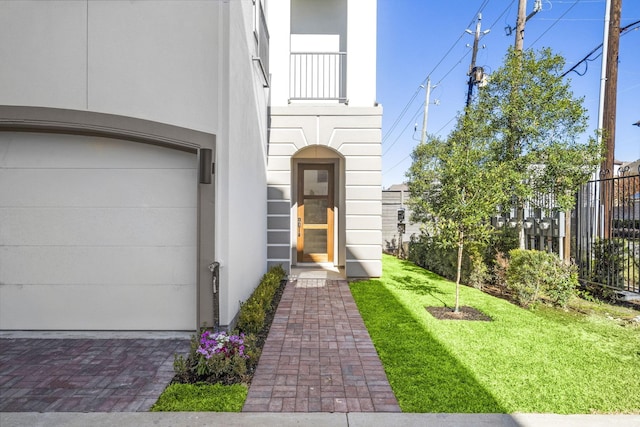 view of exterior entry featuring a garage and a lawn