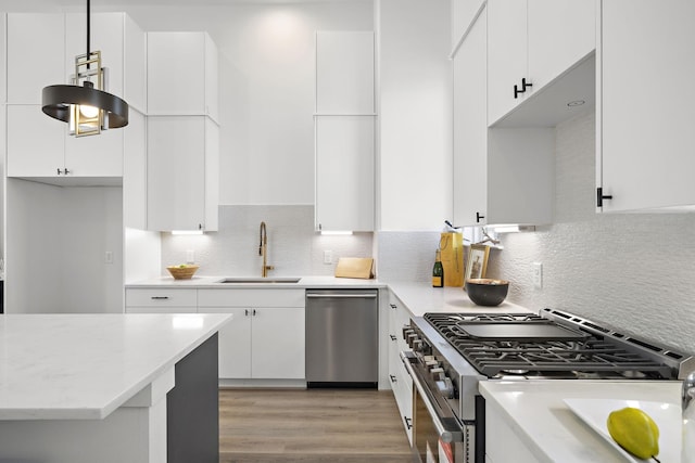 kitchen featuring sink, light wood-type flooring, appliances with stainless steel finishes, white cabinets, and backsplash