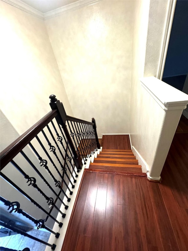 stairway featuring crown molding and hardwood / wood-style flooring