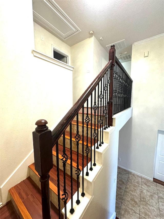 stairs with a textured ceiling and tile patterned flooring