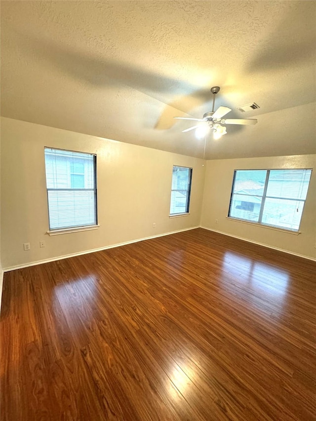 empty room with ceiling fan, dark hardwood / wood-style flooring, and a healthy amount of sunlight