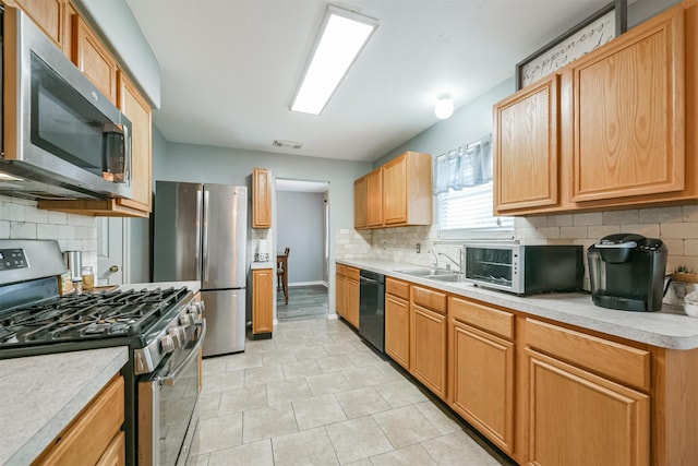 kitchen featuring sink, tasteful backsplash, light tile patterned floors, and appliances with stainless steel finishes