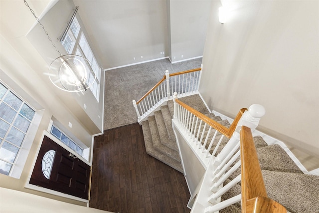 staircase with hardwood / wood-style flooring, a towering ceiling, and a chandelier