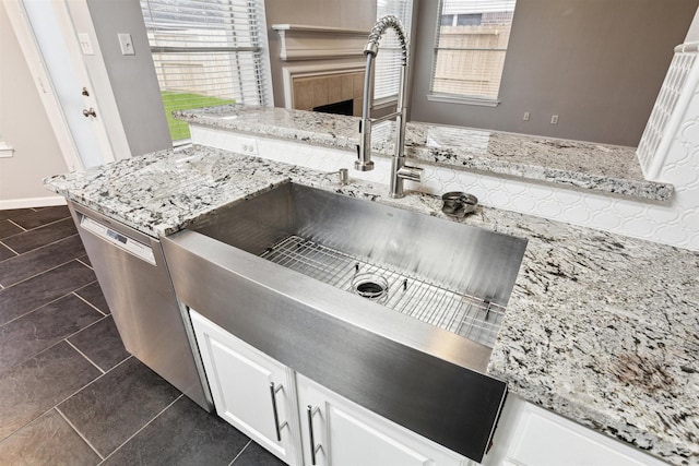 kitchen with white cabinetry, light stone counters, and stainless steel dishwasher