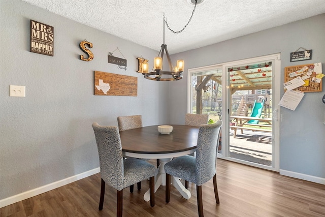 dining space featuring hardwood / wood-style flooring, a textured ceiling, and an inviting chandelier