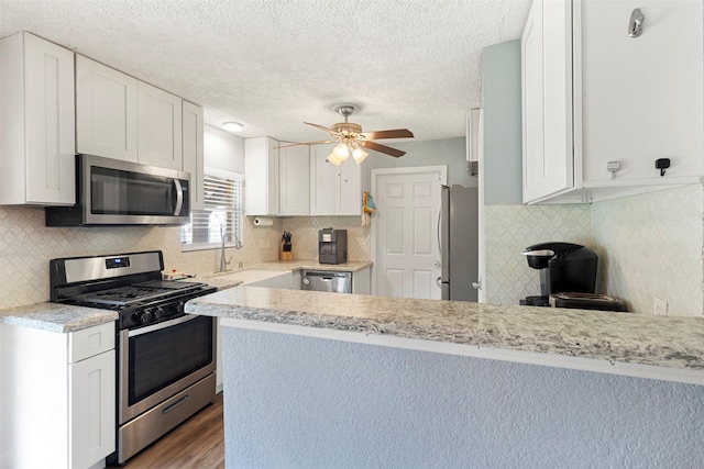 kitchen with kitchen peninsula, sink, white cabinetry, and stainless steel appliances