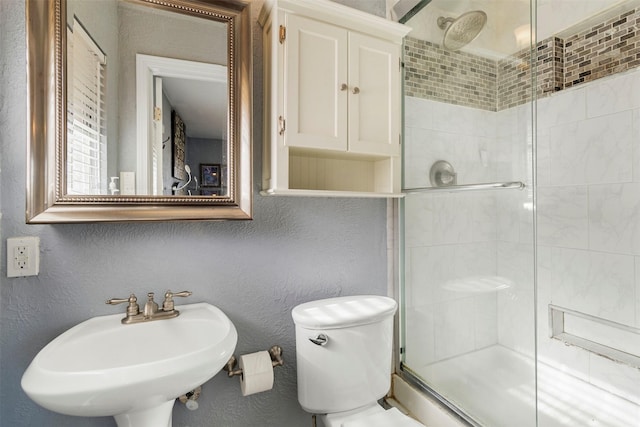 bathroom with sink, a shower with shower door, and toilet