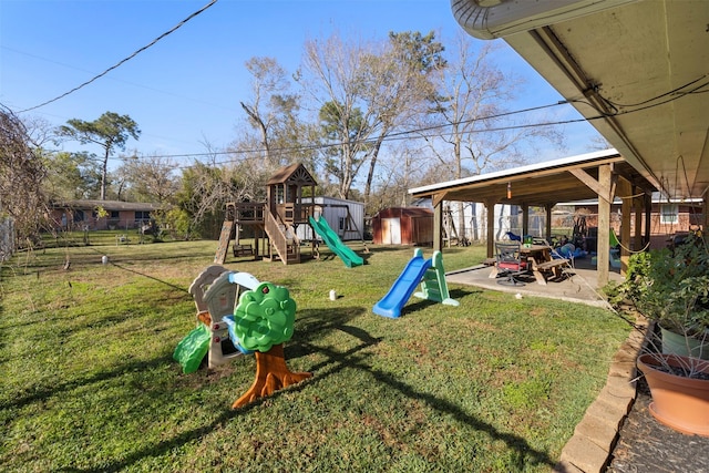 view of play area featuring a patio area, a lawn, and a storage shed