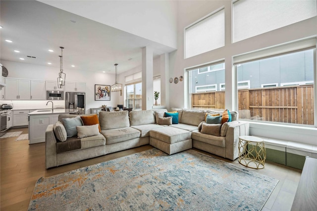 living area featuring recessed lighting, a notable chandelier, a high ceiling, and wood finished floors