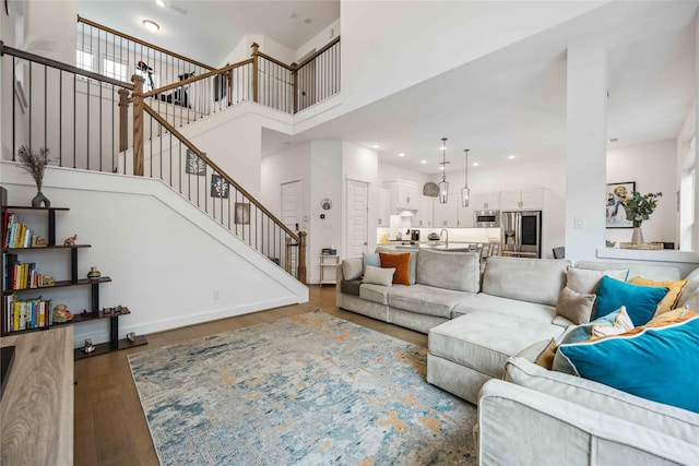 living area featuring recessed lighting, wood finished floors, a towering ceiling, baseboards, and stairway