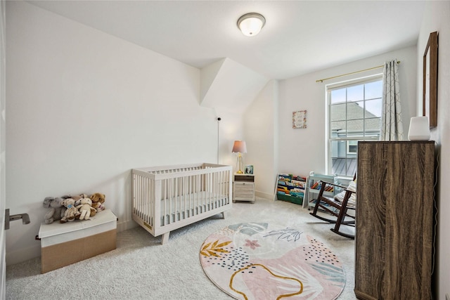 carpeted bedroom featuring a crib and baseboards