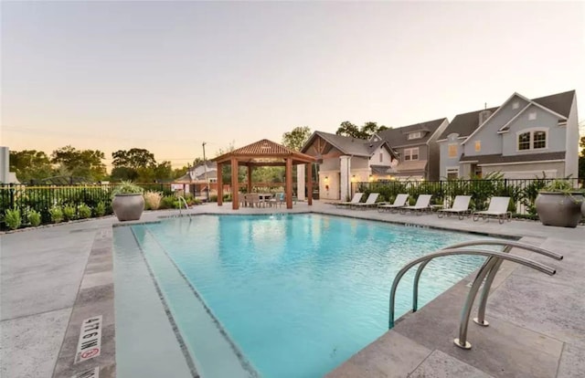 community pool featuring a gazebo, a patio, fence, and a residential view