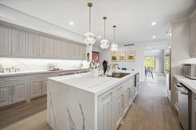 kitchen with a center island, light hardwood / wood-style floors, decorative backsplash, pendant lighting, and stainless steel appliances