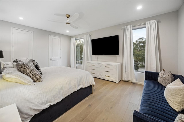 bedroom with ceiling fan, multiple windows, and light hardwood / wood-style flooring