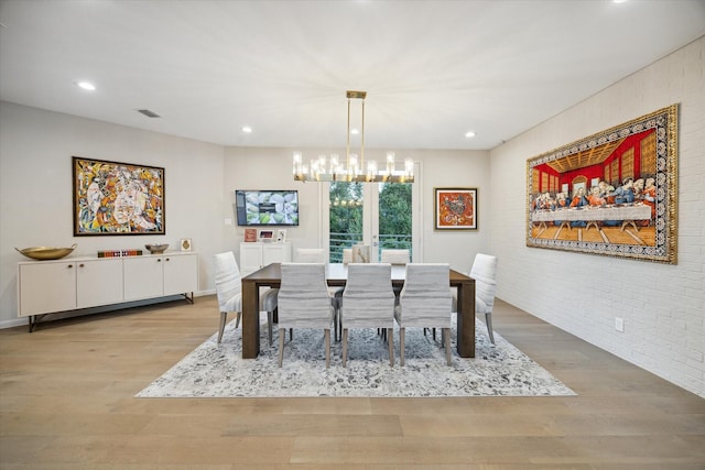 dining area with light hardwood / wood-style floors, a chandelier, brick wall, and french doors