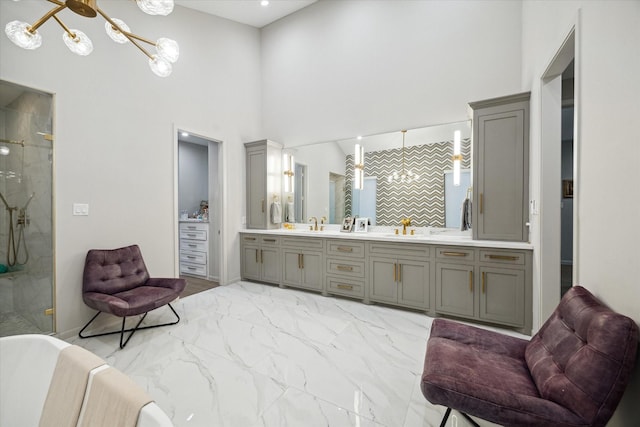 bathroom featuring an enclosed shower, vanity, a towering ceiling, and an inviting chandelier