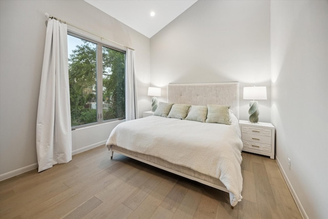 bedroom with vaulted ceiling, light hardwood / wood-style flooring, and multiple windows