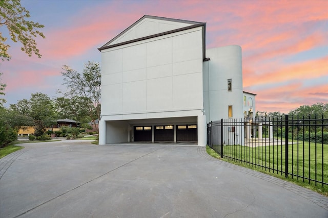 property exterior at dusk with a garage and a yard