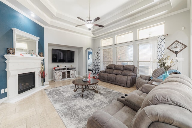 living room featuring ceiling fan, ornamental molding, and a tray ceiling